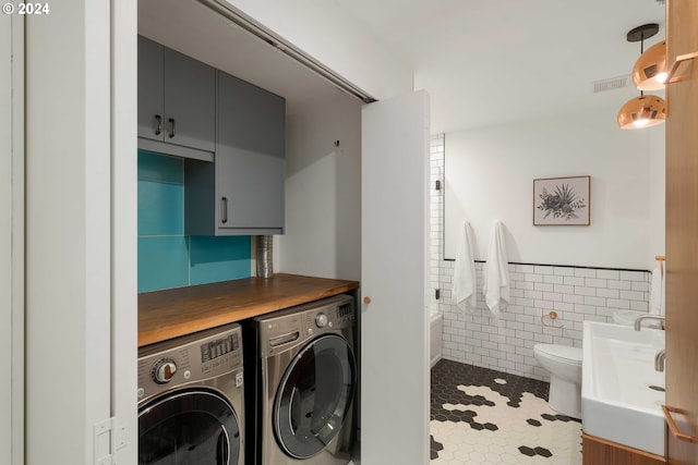 laundry area featuring tile walls, tile patterned flooring, and washer and clothes dryer