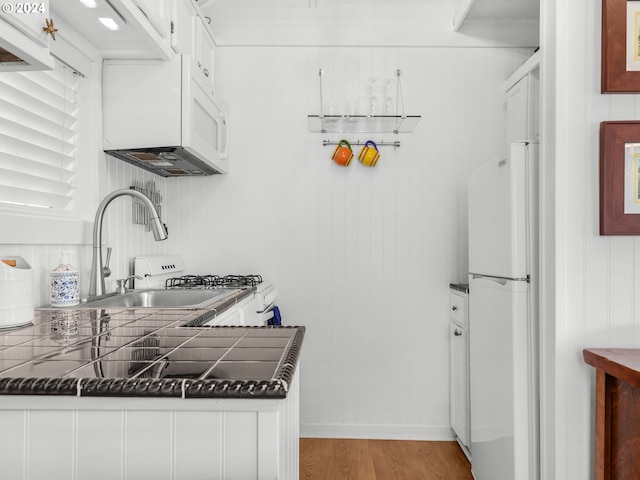 kitchen with sink, white cabinetry, light wood-type flooring, and white refrigerator