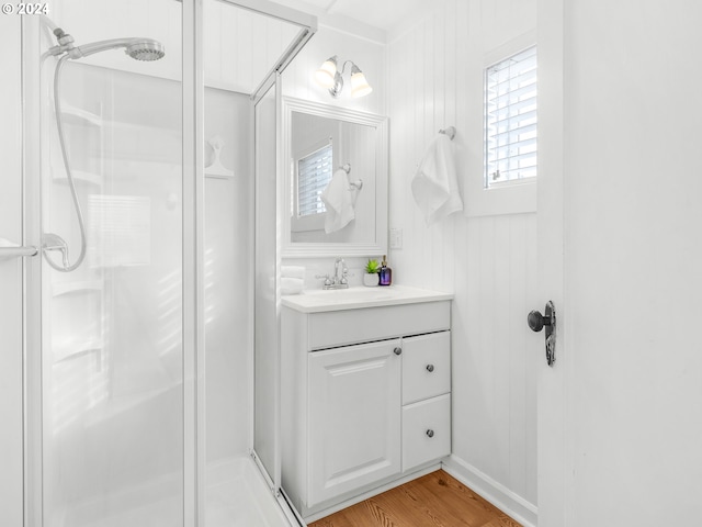 bathroom featuring vanity, hardwood / wood-style flooring, a shower with shower door, and wooden walls