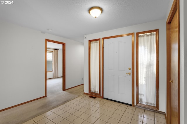 entrance foyer featuring light carpet and a textured ceiling