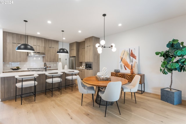 dining area featuring light hardwood / wood-style flooring, a notable chandelier, and a fireplace