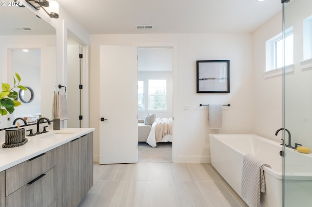 bathroom featuring vanity, a tub to relax in, tile patterned floors, and plenty of natural light