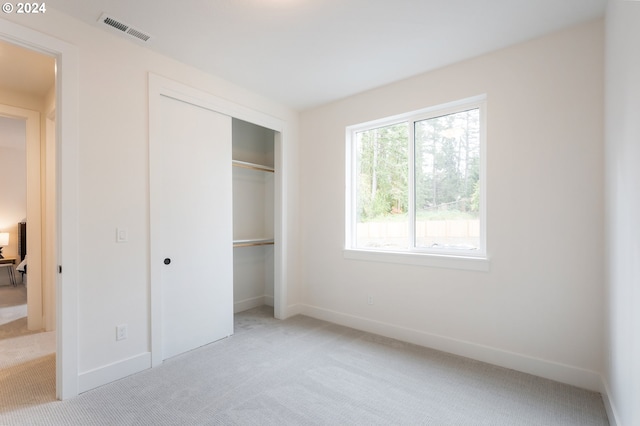 unfurnished bedroom with a closet and light colored carpet