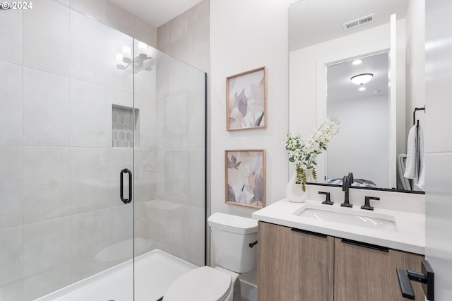 bathroom featuring toilet, an enclosed shower, and vanity