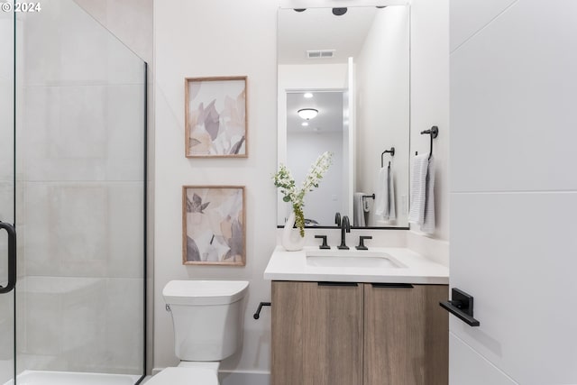 bathroom featuring vanity, toilet, and a shower with shower door