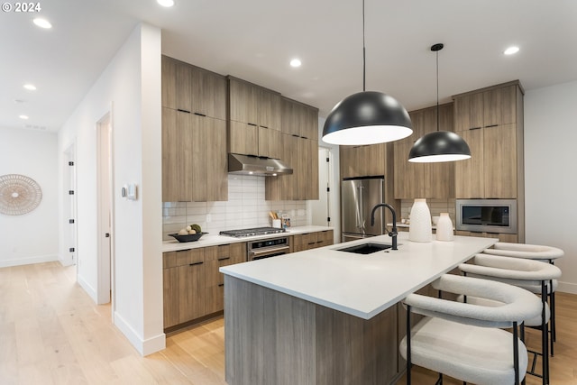 kitchen with white cabinets, a tiled fireplace, a center island with sink, an inviting chandelier, and light hardwood / wood-style floors