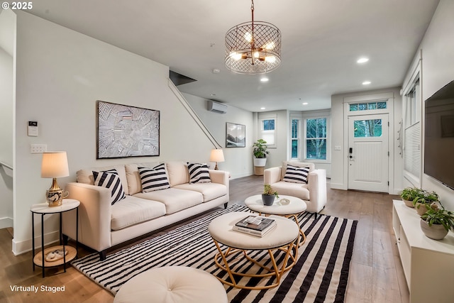 living area with a wall mounted air conditioner, wood finished floors, recessed lighting, baseboards, and a chandelier