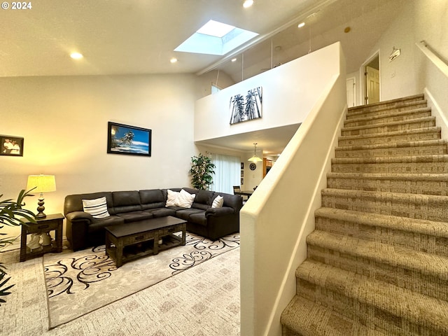 carpeted living room with high vaulted ceiling and a skylight