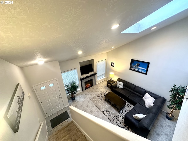146 28th St, Long Beach, WA 98631 - carpeted living room with a warm lit fireplace, a skylight, recessed lighting, a textured ceiling, and baseboards