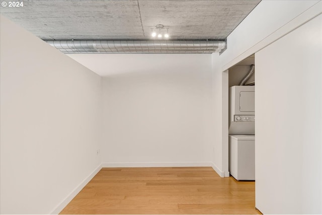 hallway with hardwood / wood-style floors and stacked washer / drying machine