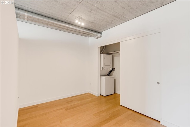 basement with wood-type flooring and stacked washer and clothes dryer