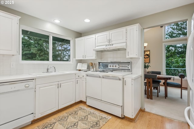 kitchen with white appliances, light countertops, a healthy amount of sunlight, under cabinet range hood, and a sink