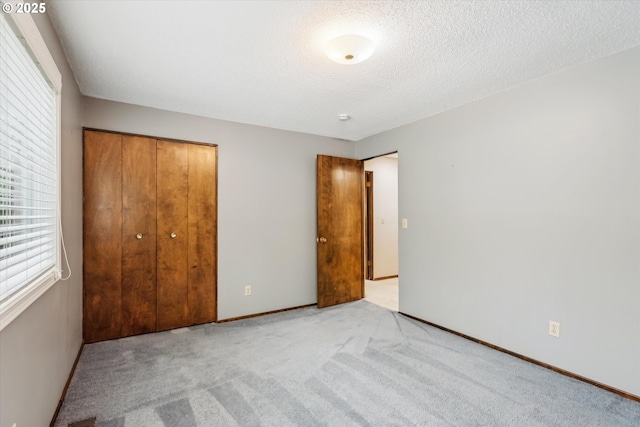 unfurnished bedroom featuring a textured ceiling, carpet floors, a closet, and baseboards