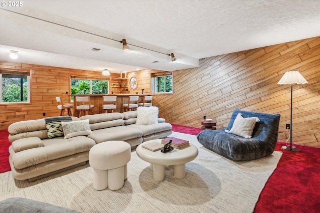 living room with wood walls, visible vents, indoor bar, and a textured ceiling