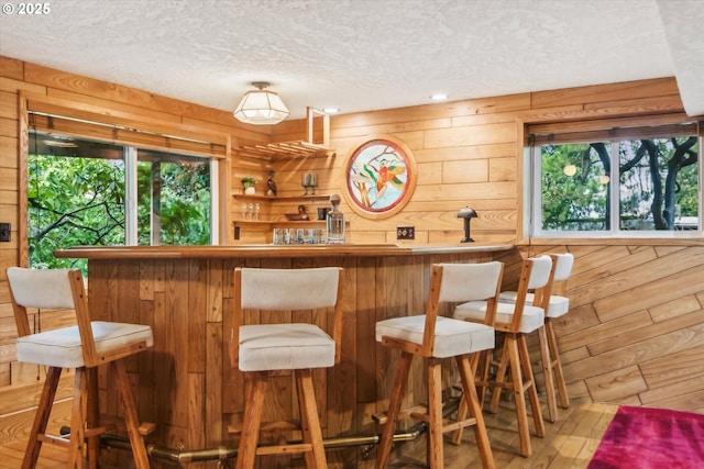 bar with a bar, wood walls, and a textured ceiling