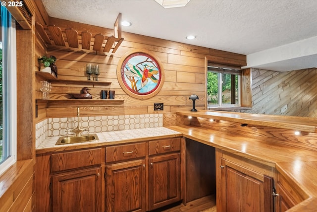 bar with wood walls, a textured ceiling, and a sink