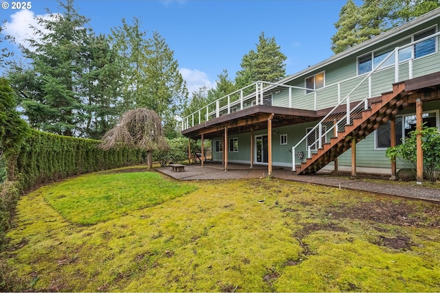 back of house featuring a patio, stairway, a wooden deck, and a lawn