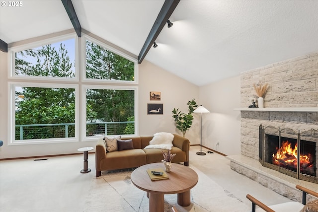 living area featuring a healthy amount of sunlight, carpet flooring, vaulted ceiling with beams, and a stone fireplace