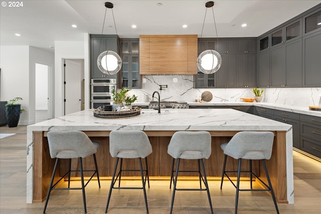 kitchen with a kitchen bar, a large island, stainless steel double oven, and light stone counters