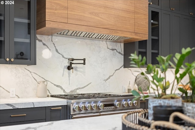 interior space with backsplash, custom exhaust hood, high end stove, and light stone countertops