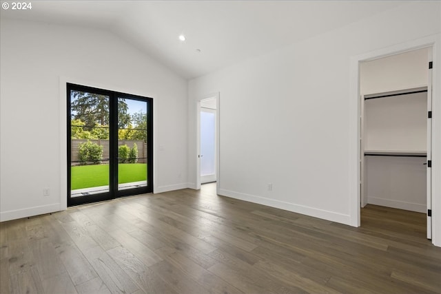 unfurnished bedroom with lofted ceiling, dark hardwood / wood-style floors, a spacious closet, access to outside, and a closet