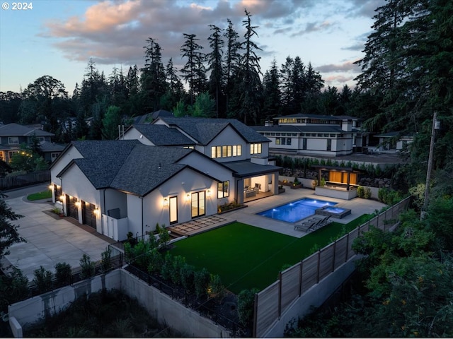 back house at dusk with a swimming pool with hot tub, a yard, and a patio area