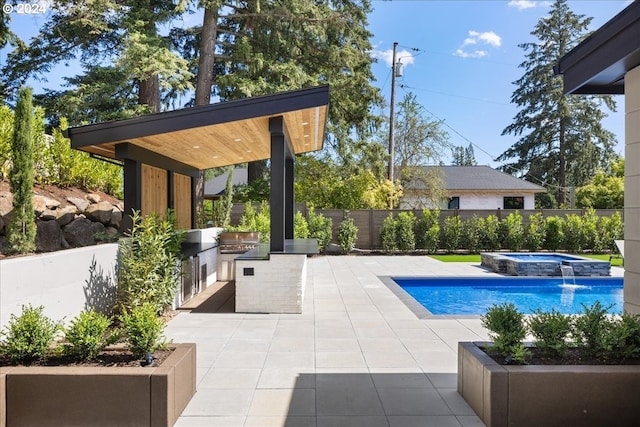 view of swimming pool with an in ground hot tub, exterior kitchen, and a patio