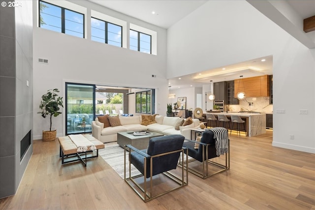 living room with a towering ceiling, a fireplace, and light hardwood / wood-style flooring