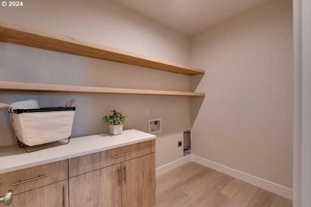 laundry area featuring cabinets, light hardwood / wood-style floors, hookup for a washing machine, and hookup for an electric dryer