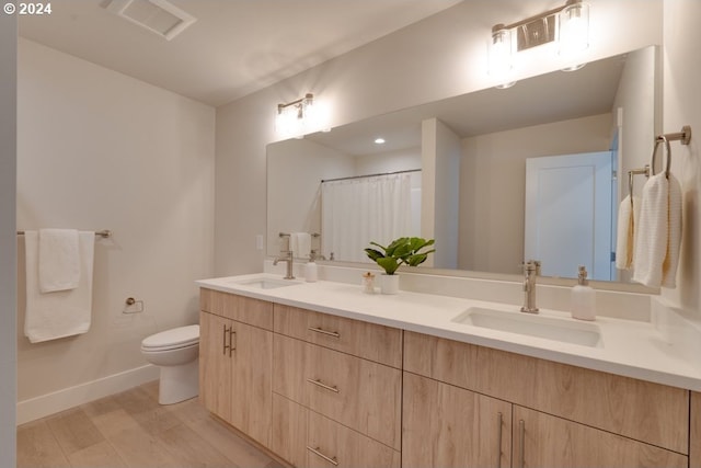 bathroom featuring toilet, vanity, and hardwood / wood-style flooring