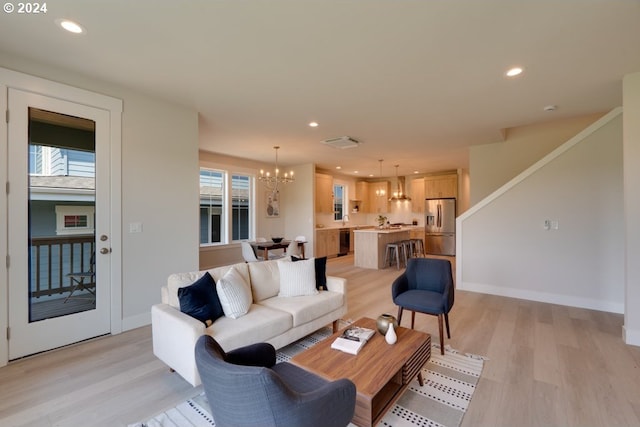 living room with a chandelier, light hardwood / wood-style floors, and a healthy amount of sunlight