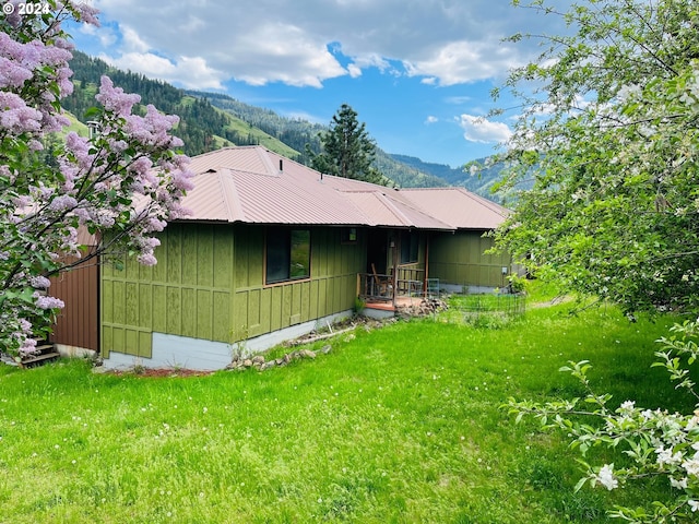 back of property featuring a mountain view and a yard