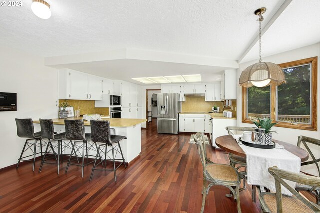 dining area with dark hardwood / wood-style floors, vaulted ceiling, and a textured ceiling