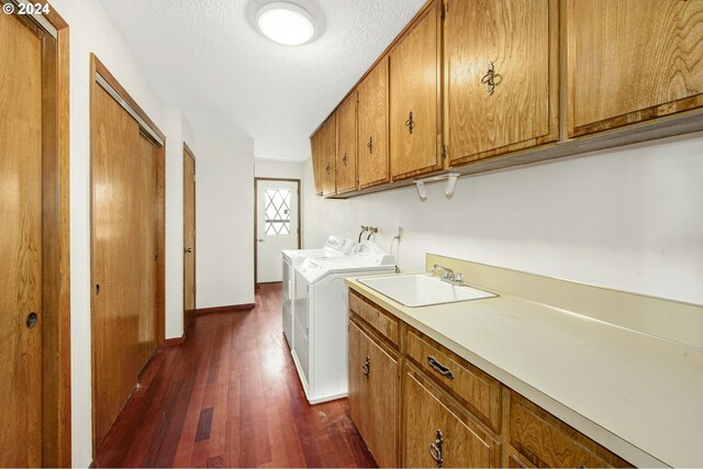 washroom with sink, washing machine and dryer, cabinets, a textured ceiling, and dark wood-type flooring