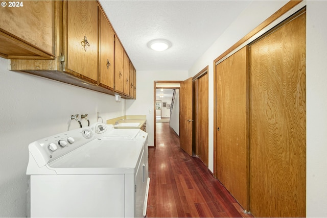 washroom featuring sink, dark wood-type flooring, washing machine and clothes dryer, and cabinets