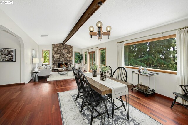 dining room with hardwood / wood-style flooring, lofted ceiling with beams, and a stone fireplace