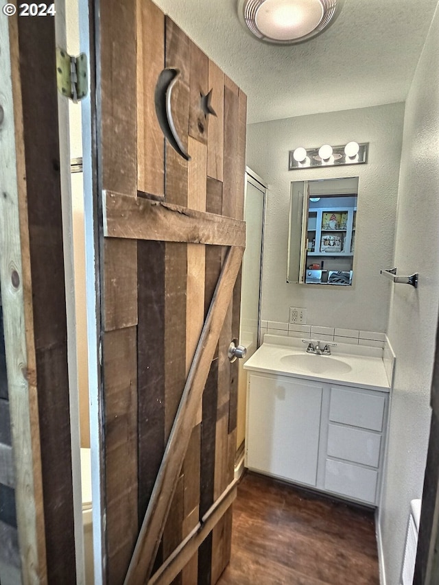 bathroom featuring vanity, wood-type flooring, and a textured ceiling