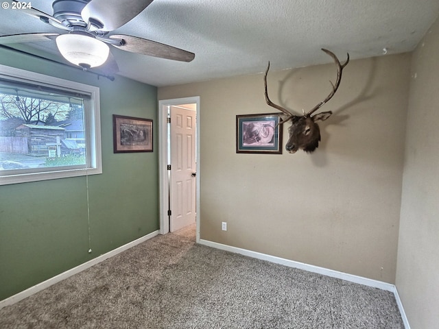 empty room with ceiling fan, carpet floors, and a textured ceiling