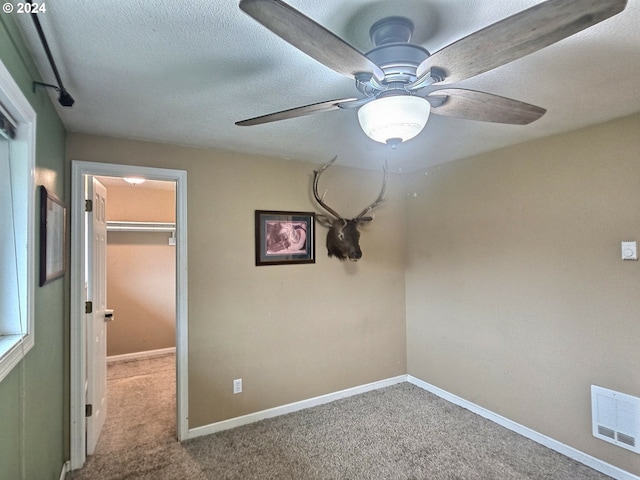 interior space with a walk in closet, light colored carpet, a closet, and ceiling fan