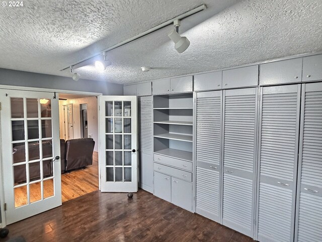 interior space featuring rail lighting, wood-type flooring, a textured ceiling, and french doors