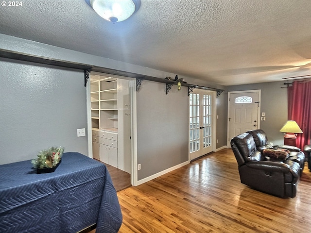 living room featuring french doors, a textured ceiling, and hardwood / wood-style flooring