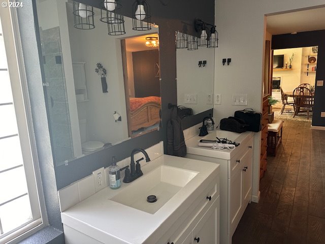 bathroom featuring hardwood / wood-style flooring, toilet, vanity, and a chandelier