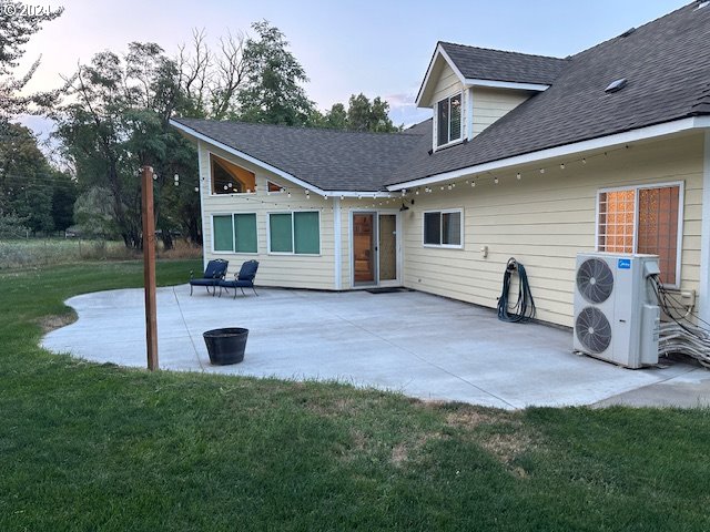 rear view of property with ac unit, a patio, and a lawn