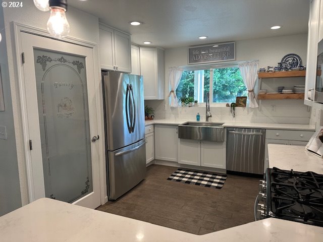 kitchen featuring dark hardwood / wood-style floors, backsplash, white cabinetry, appliances with stainless steel finishes, and sink