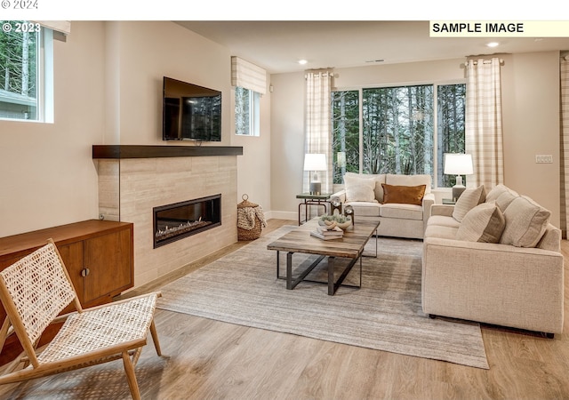 living room with a tiled fireplace, plenty of natural light, and hardwood / wood-style floors