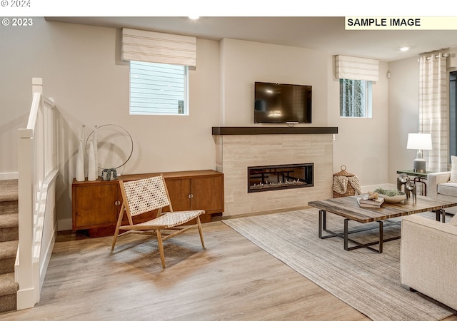 living room featuring a tile fireplace and light wood-type flooring