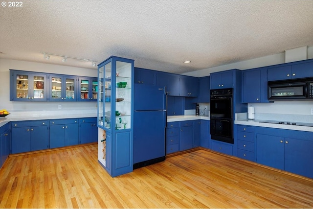 kitchen featuring black appliances, blue cabinets, a textured ceiling, and light hardwood / wood-style flooring