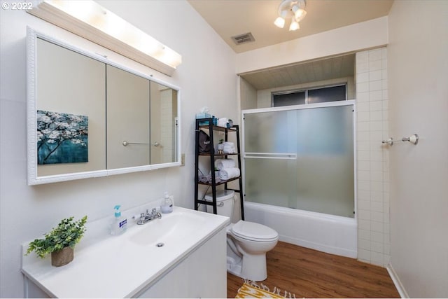 full bathroom featuring combined bath / shower with glass door, hardwood / wood-style floors, vanity, and toilet