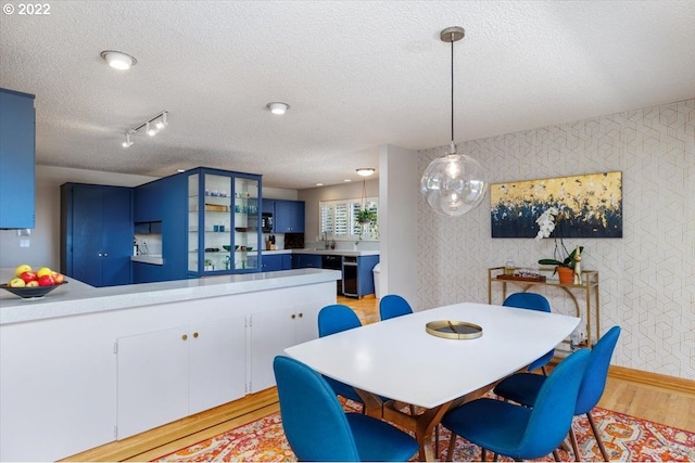 dining space featuring light wood-type flooring, a textured ceiling, and sink