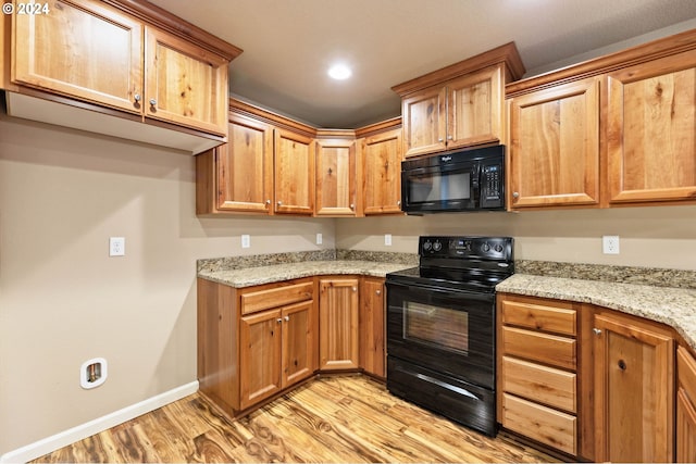 kitchen with black appliances, light stone counters, and light wood-type flooring